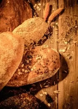 Various types of bread on a wooden table.